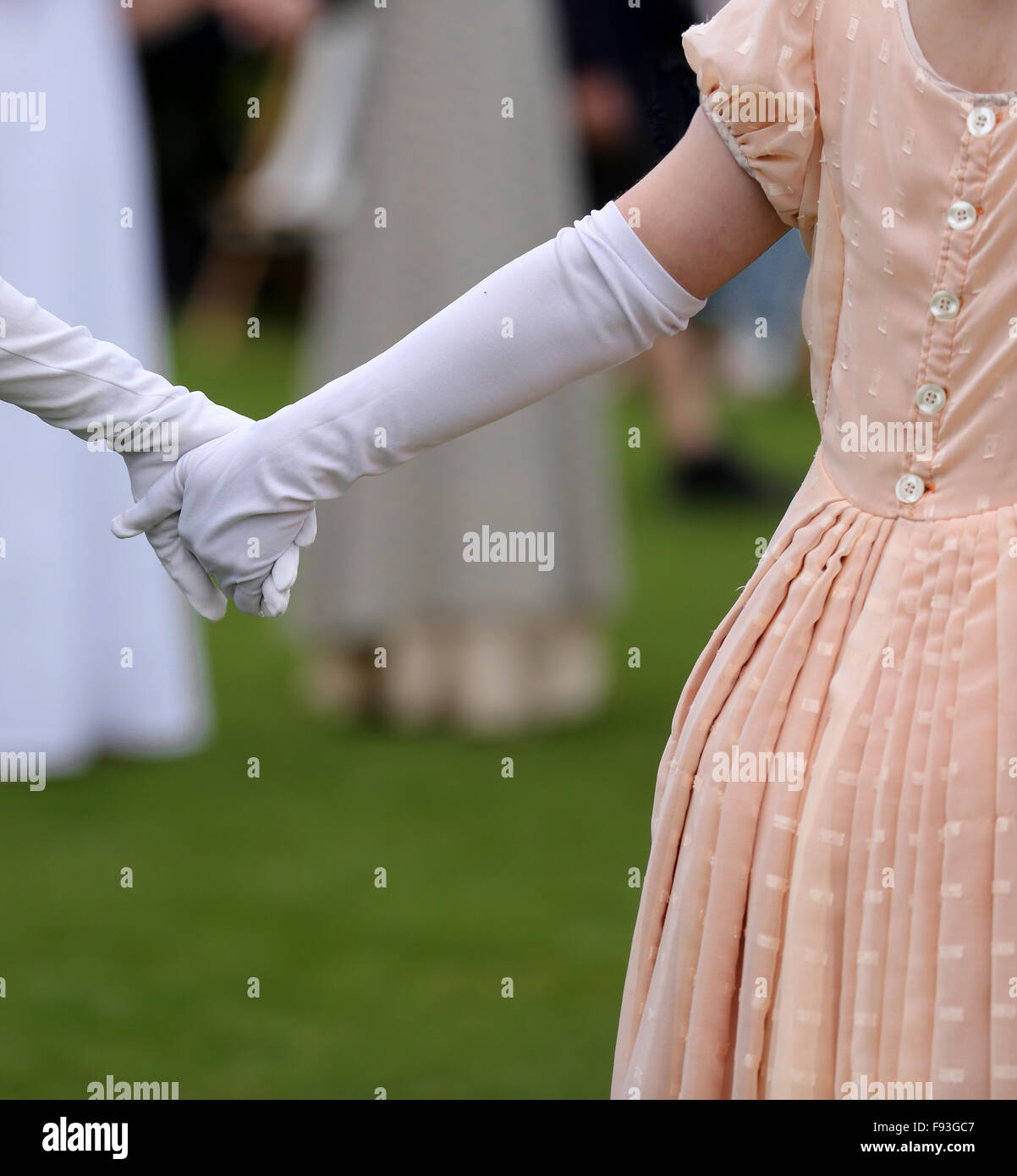 Gloved young women holding hands in 18th century period costume. Stock Photo