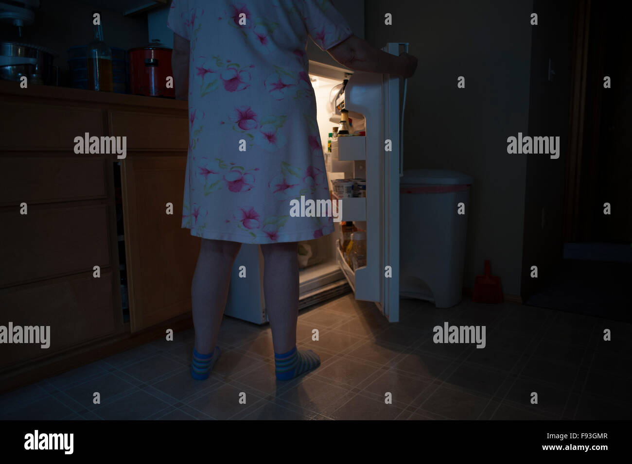 Woman opening refrigerator door at night to get a snack Stock Photo