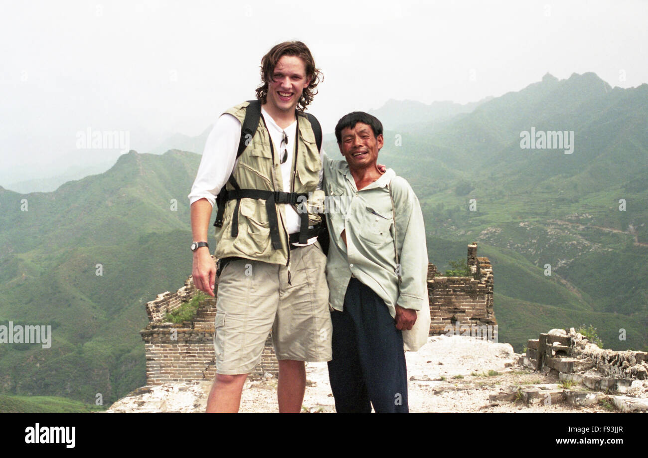 A tall western man stands next a chinese man on the great wall of china Stock Photo