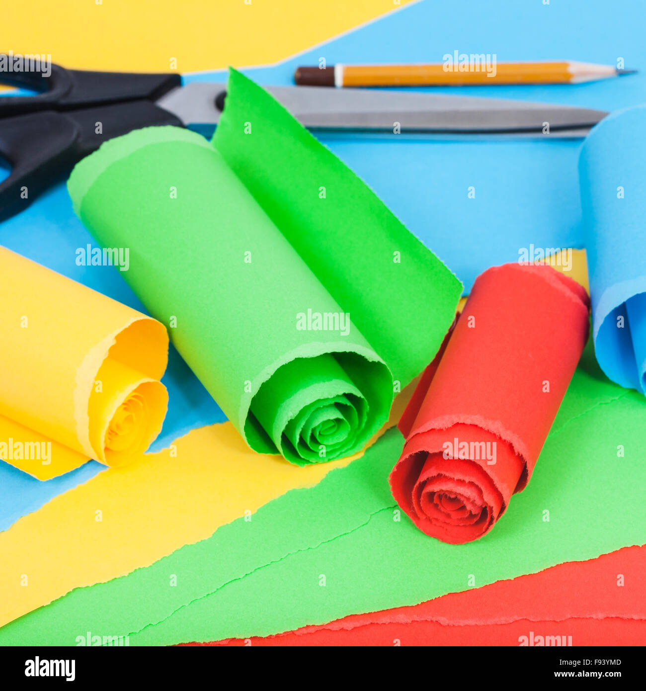 still life - scissor, pencil and rolled color paper on sheets of plain ...