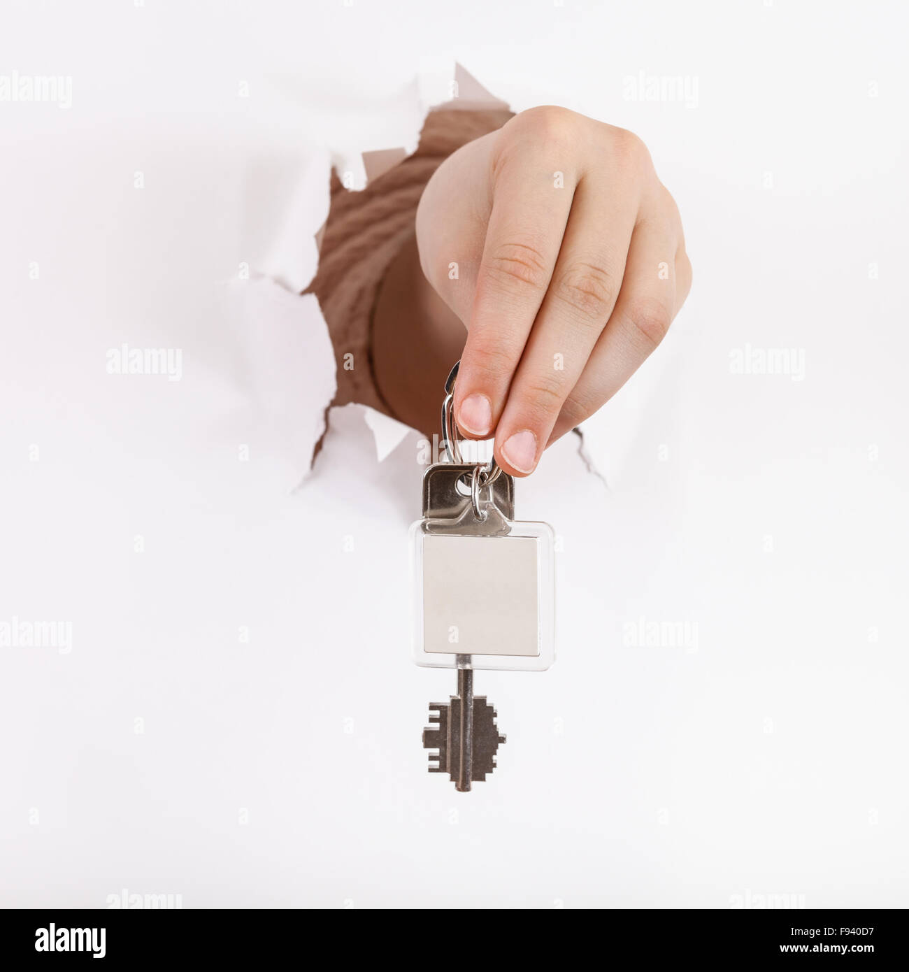 hand holds the keychain through a hole in a sheet of paper Stock Photo