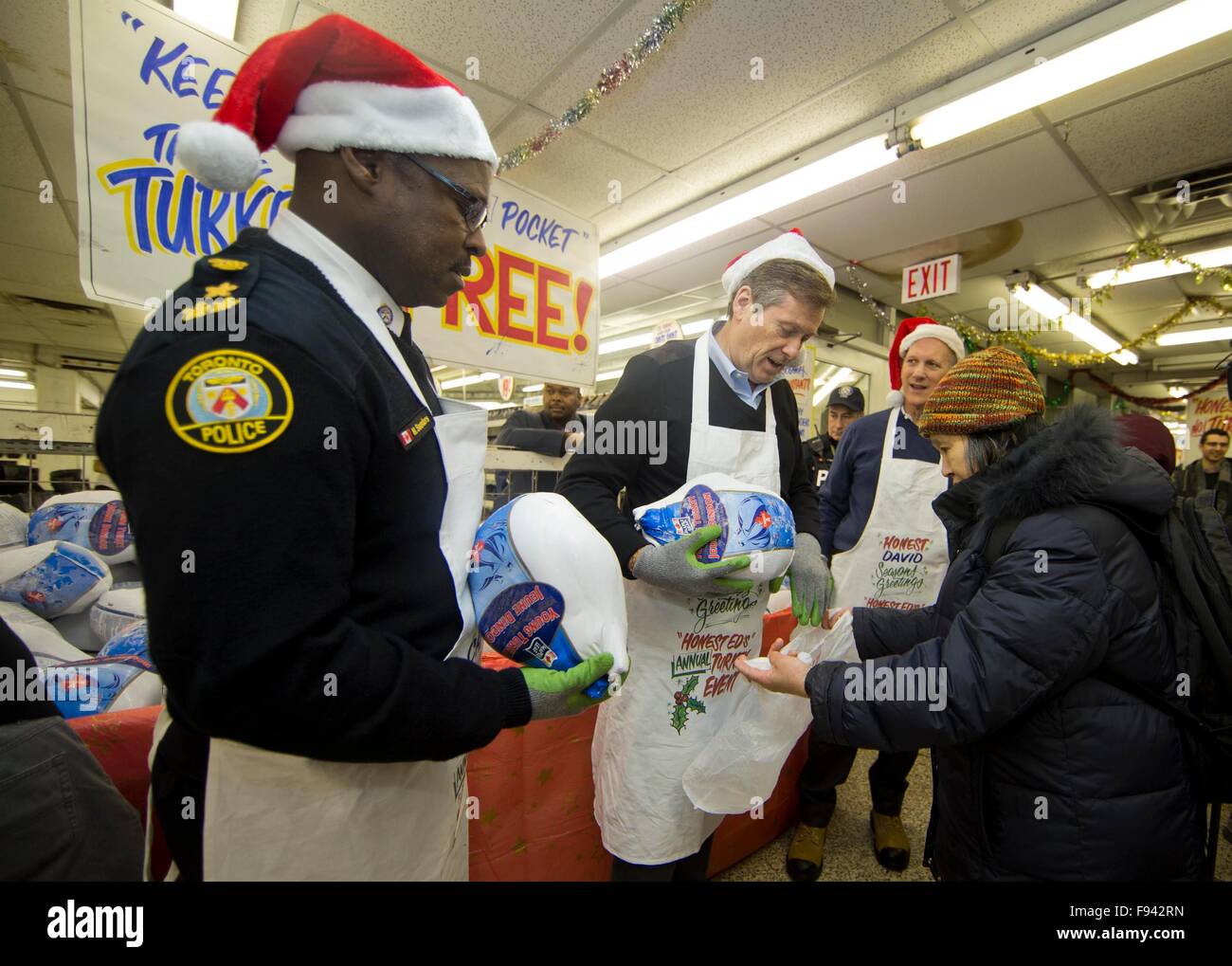 Toronto, Canada. 13th Dec, 2015. A woman receives a free turkey from Toronto Mayor John Tory (2nd L) at a local store called Honest Ed's during the store's 28th annual Christmas time turkey giveaway event in Toronto, Canada, Dec. 13, 2015. In the last giveaway of this annual event, hundreds of people around the city lined up to get one of about 1,300 free turkeys and fruitcakes from the store on Sunday. © Zou Zheng/Xinhua/Alamy Live News Stock Photo