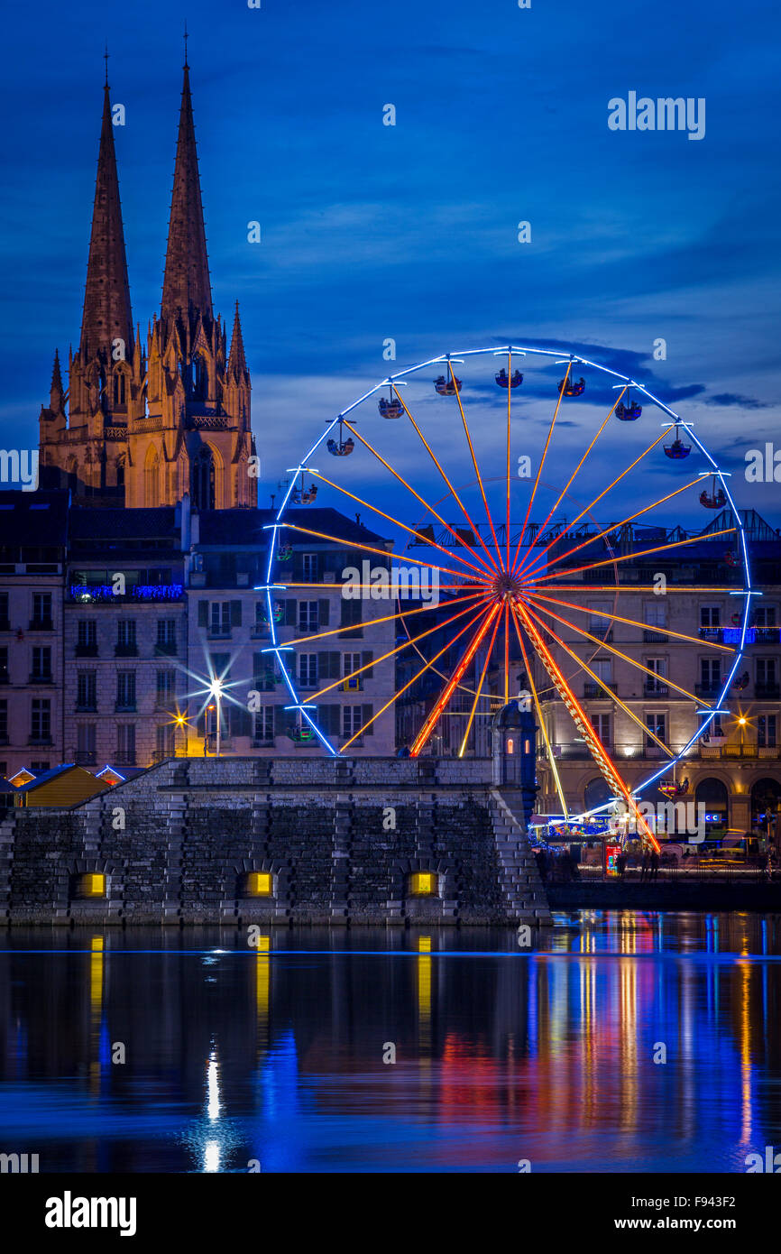 At night, a big wheel (Ferris Wheel) mirroring in water at the Adour and Nive river confluence (Bayonne - Aquitaine - France). Stock Photo