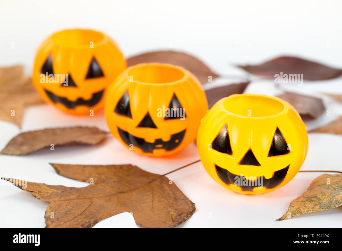 Three plastic pumpkins with autumn leafs on white background Stock Photo