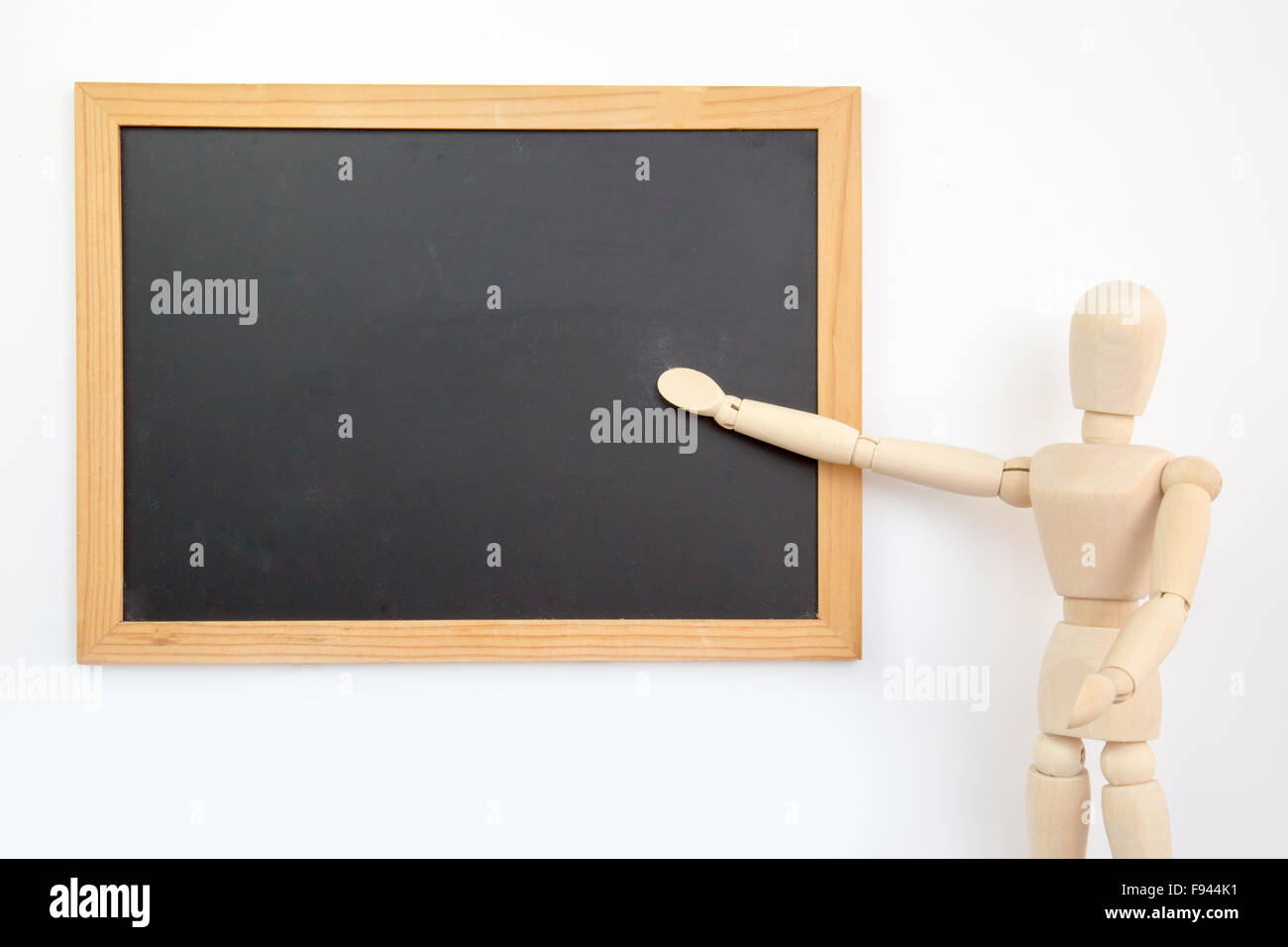 Wooden puppet businessman presents on blackboard Stock Photo