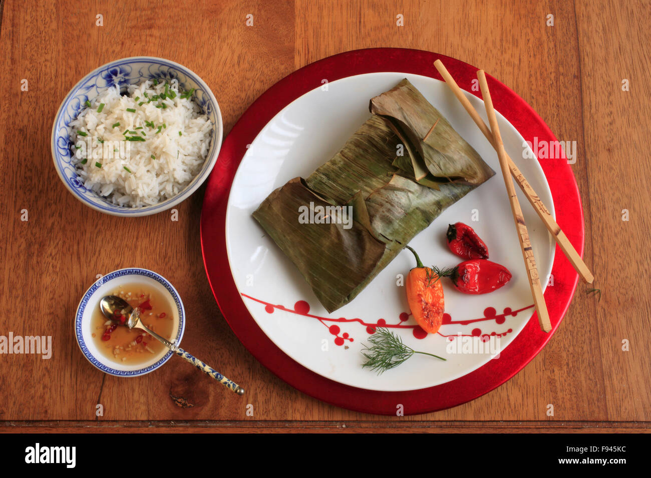 Roasted Salmon in Banana Leaves, spicy dill and lime paste, coconut rice, Vietnamese dipping sauce, peppers, Stock Photo
