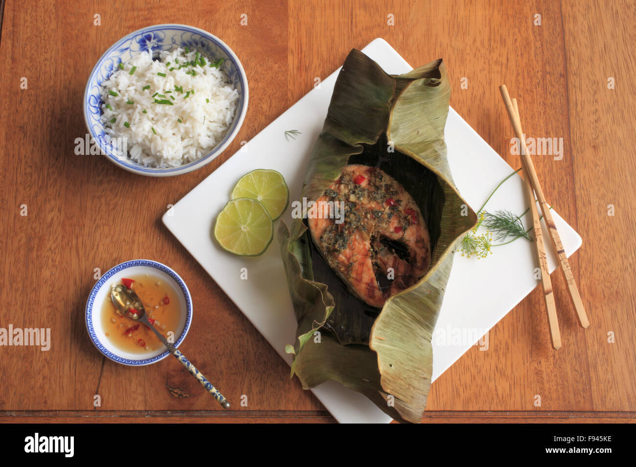 Roasted Salmon in Banana Leaves, spicy dill and lime paste, coconut rice, Vietnamese dipping sauce, peppers, Stock Photo