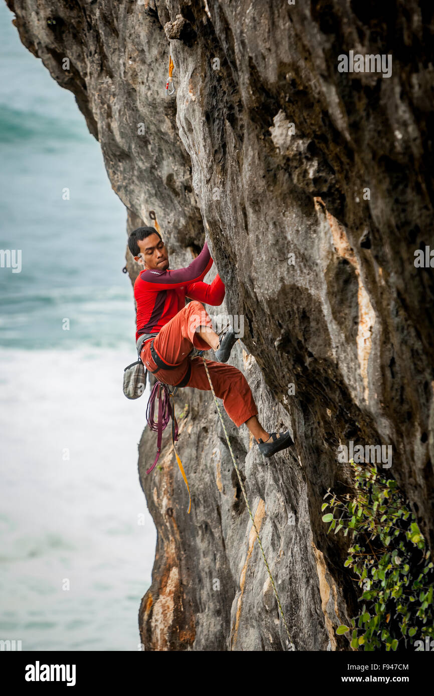 A rock climber is climbing a seaside rockface in a coastal area called