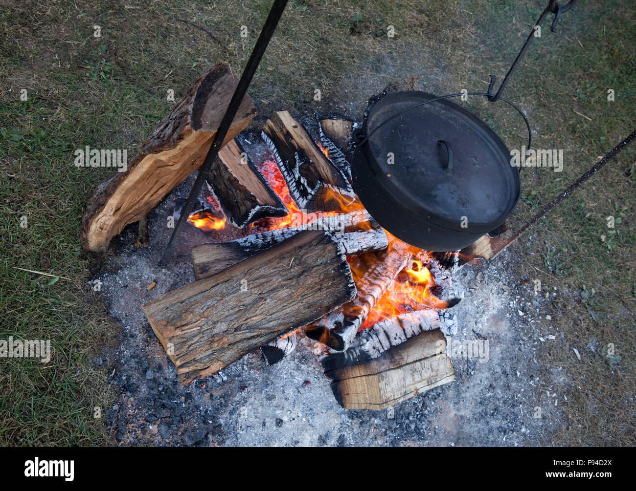 Cast iron Dutch oven hanging over a campfire to cook food Stock Photo
