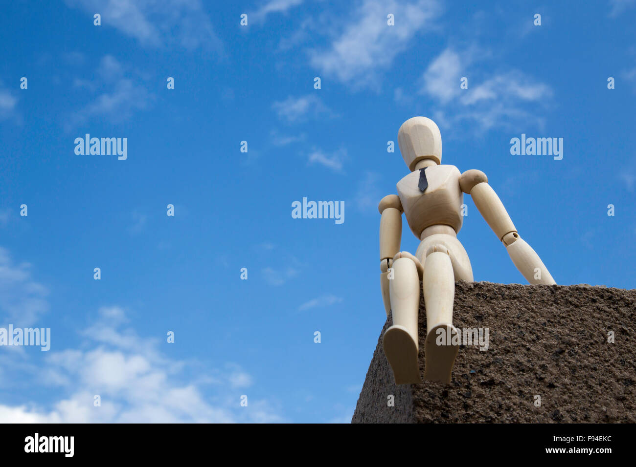 Businessman puppet on the edge of a building in front of blue sky Stock Photo