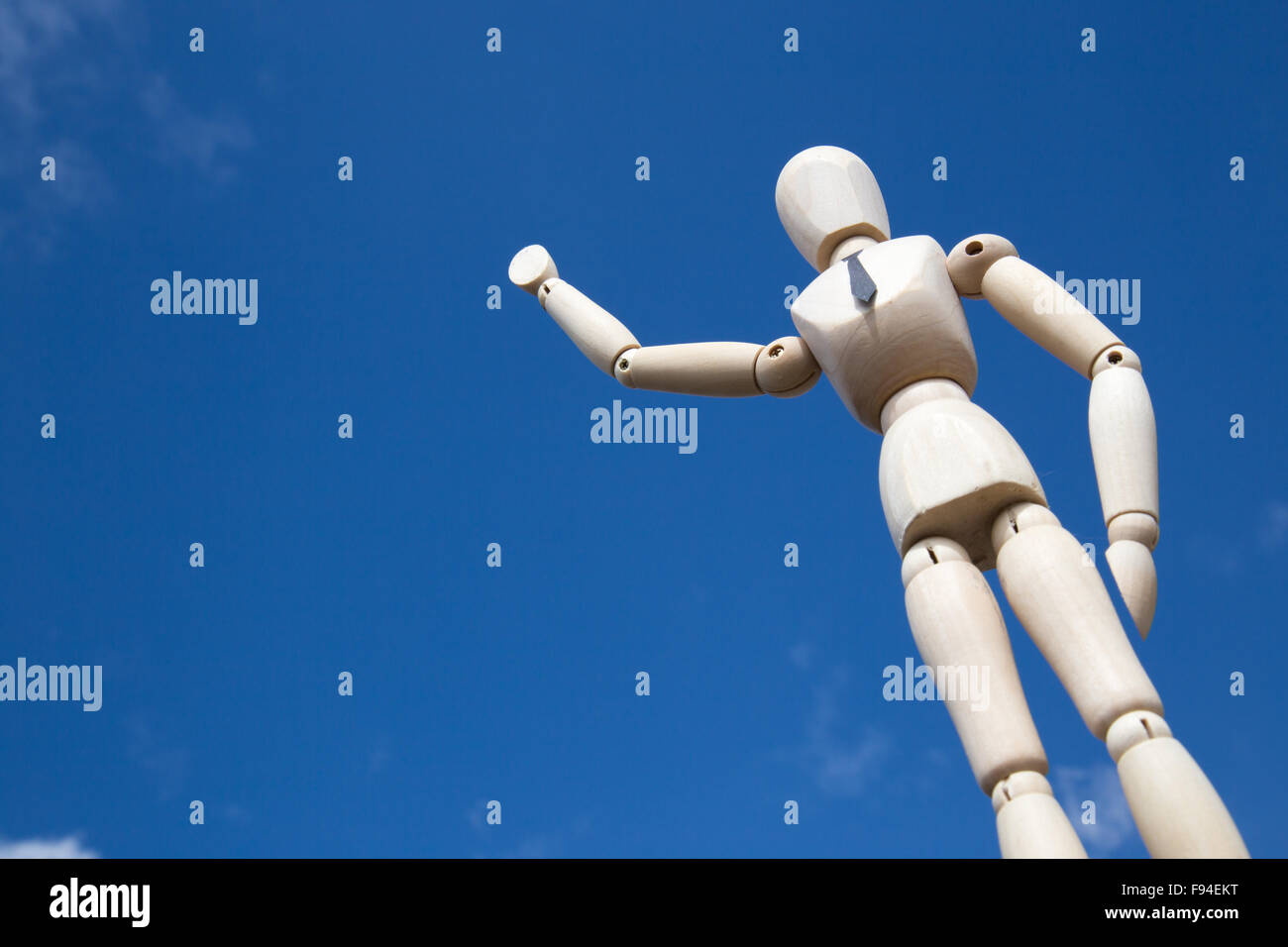 Giant businessman puppet waving in front of blue sky in sunlight Stock Photo