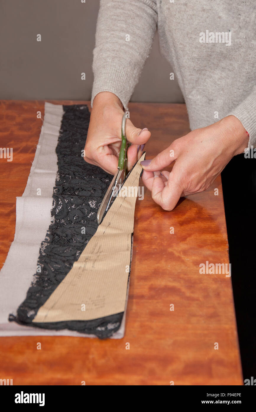 dressmaker at work cutting piece of black and grey cloth Stock Photo