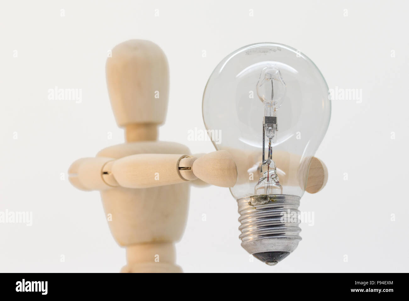 Wooden guy presenting a light bulb that is switched off Stock Photo