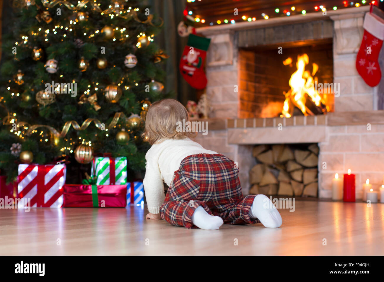 Child toddler crawling to gifts lying under Christmas tree Stock Photo