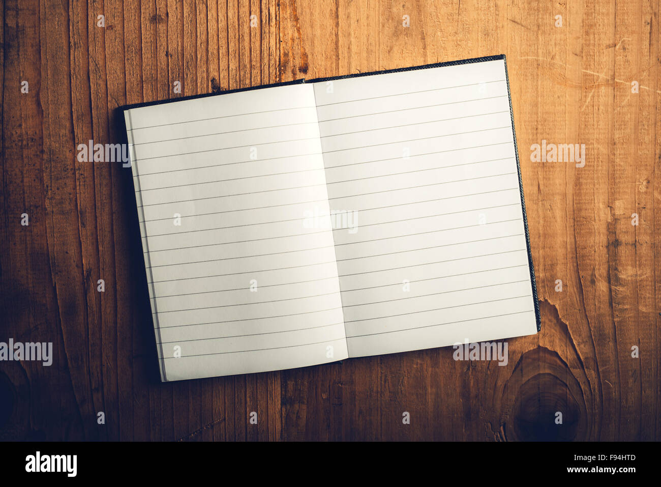 Top view of open notebook with blank pages on old wooden desk, retro toned image as copy space Stock Photo