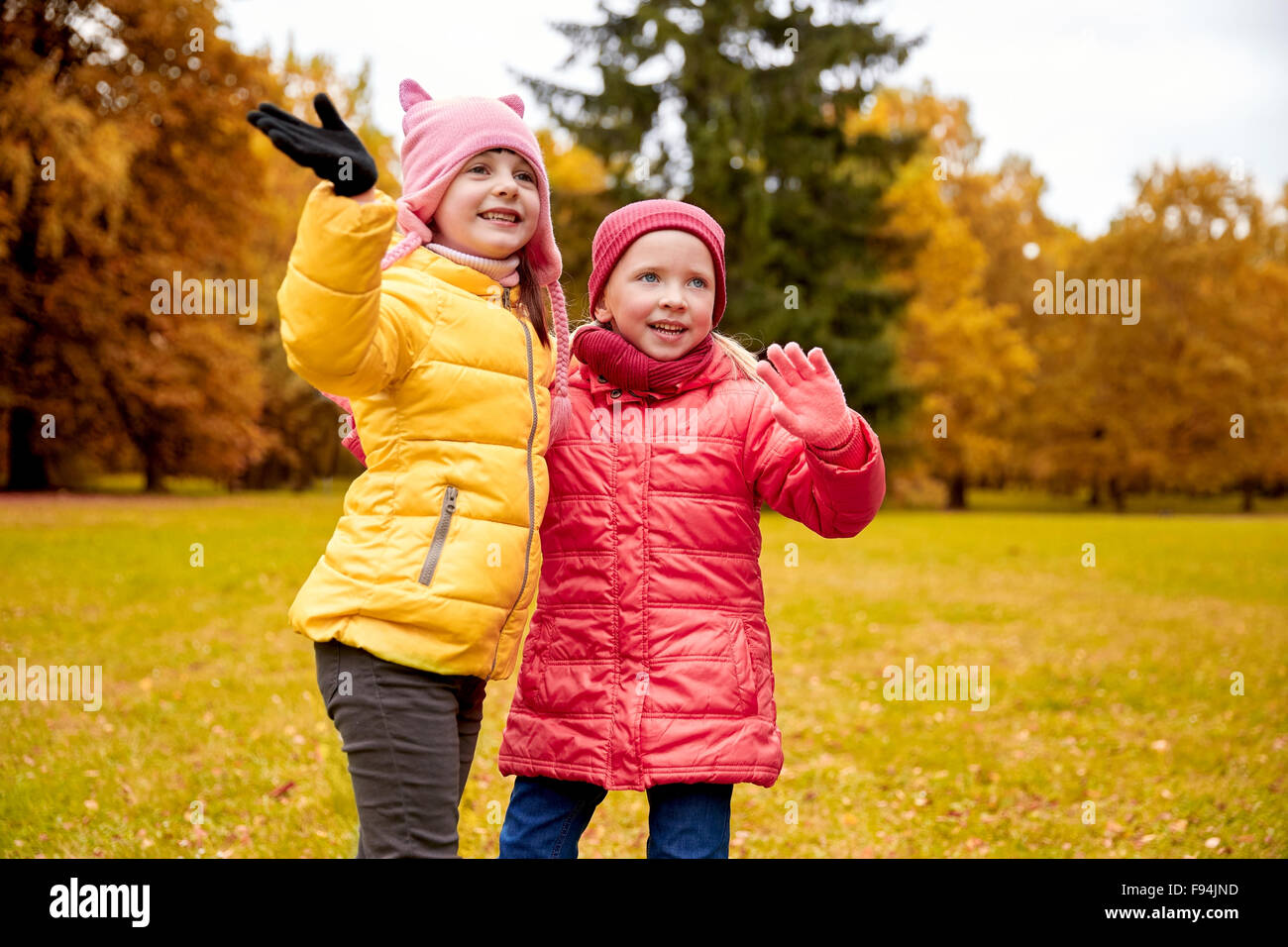two happy little girls waving hand in autumn park Stock Photo - Alamy