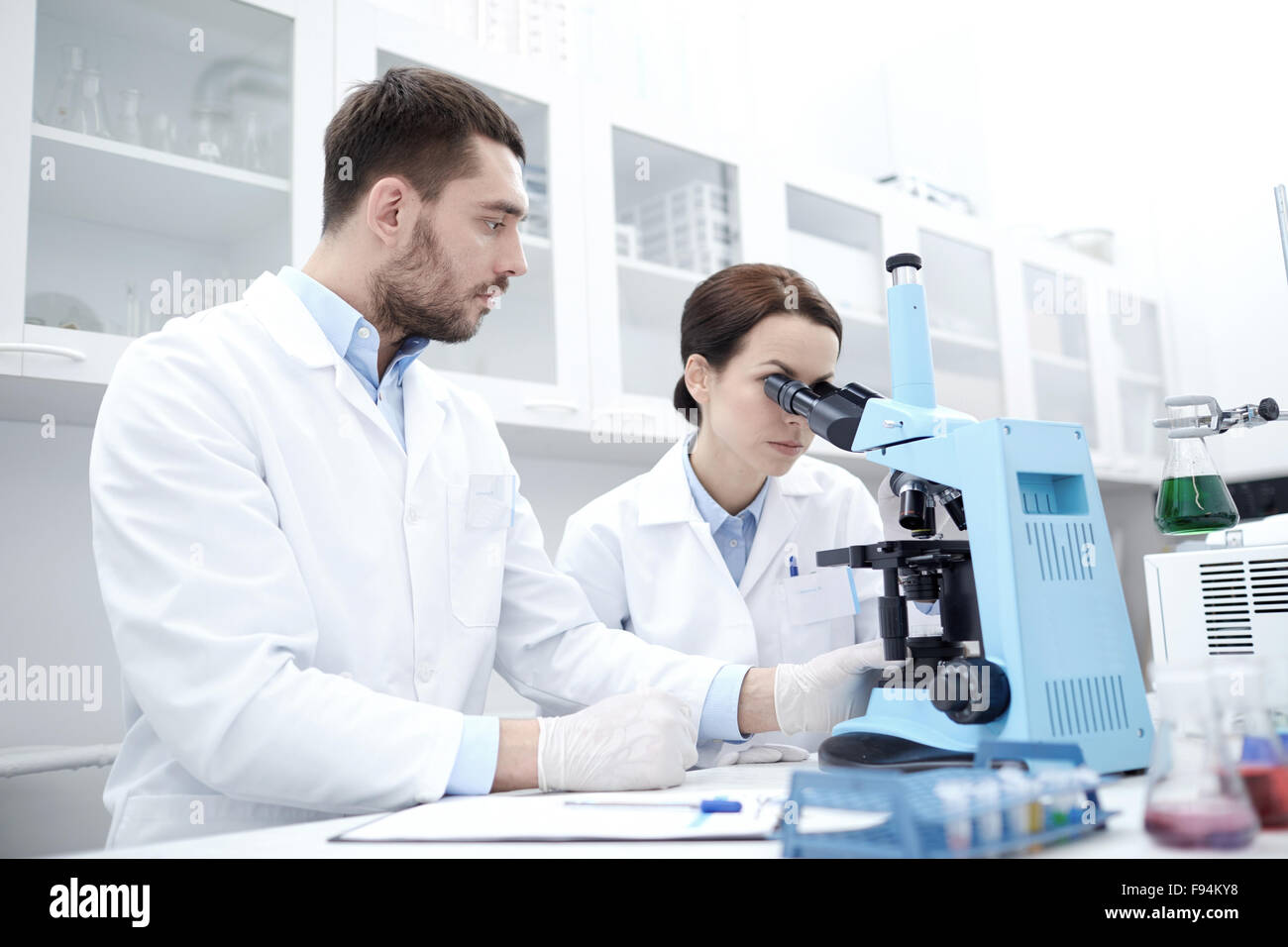scientists with clipboard and microscope in lab Stock Photo - Alamy