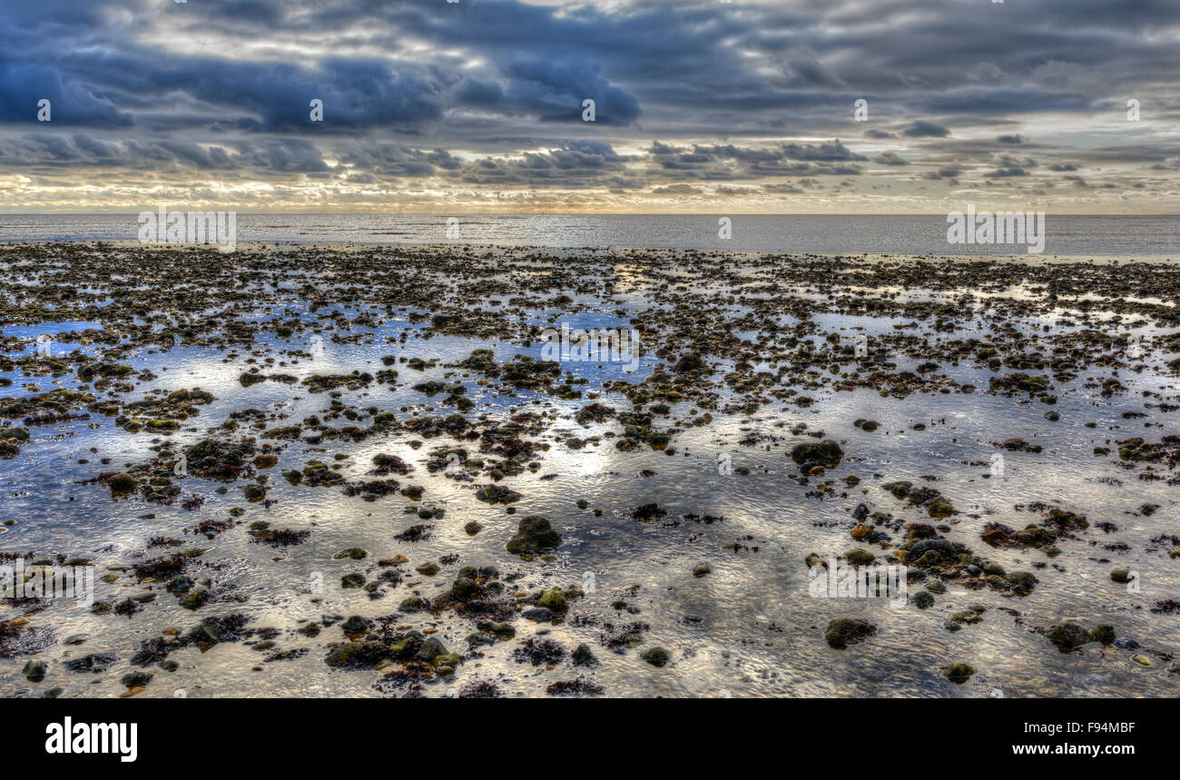 Tranquillity concept. Beach by the sea at a very low tide, with reflections of the sky in remaining water. Stock Photo