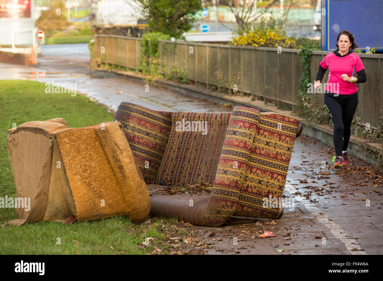 Life returns to normal. A flood damaged sofa and chair at Hardwicke Circus in Carlisle, Cumbria, with a jogger running past on Tuesday 8th December 2015, after torrential rain from storm Desmond. The storm set a new British record for rainfsll totals in a day with 341.4mm falling in 24 hours. Stock Photo