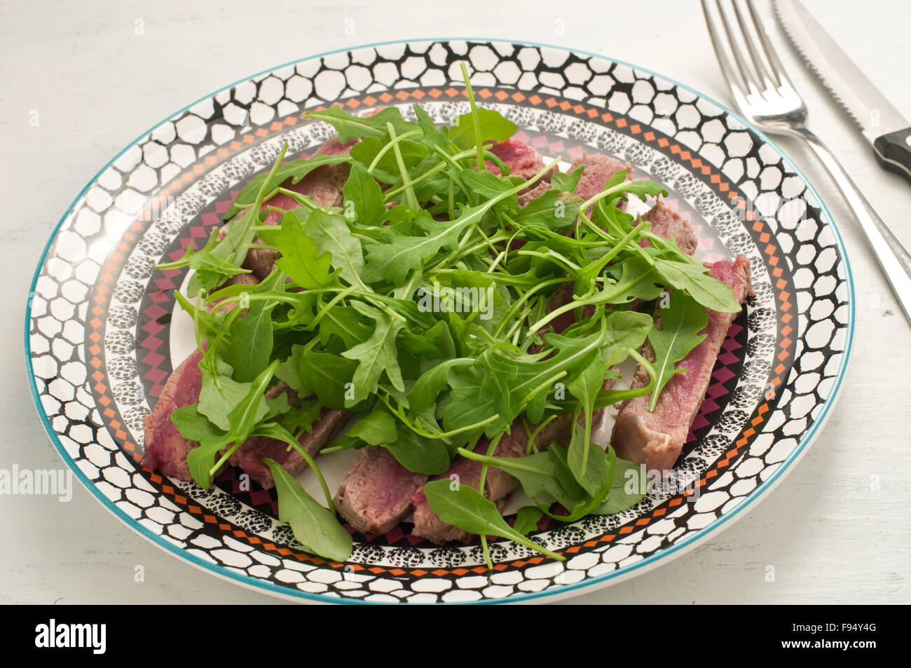 Sliced beef cooked in the oven with salt, pepper and rocket, italy
