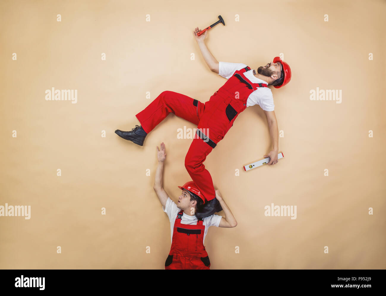 Construction workers have an accident. Funny studio poses. Stock Photo