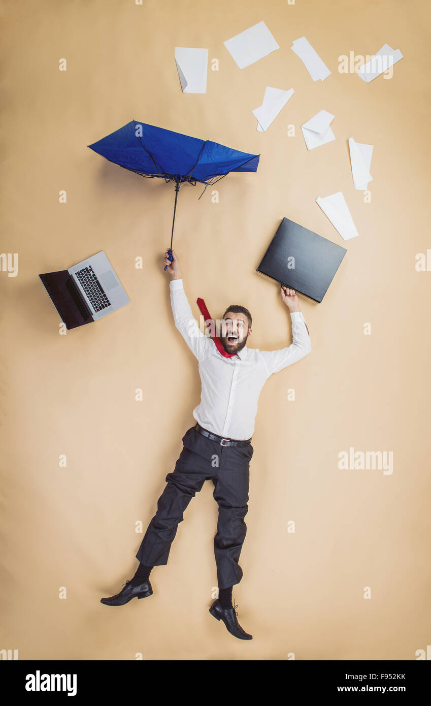 fired manager is falling down with umbrella. Man loses his job. Stock Photo