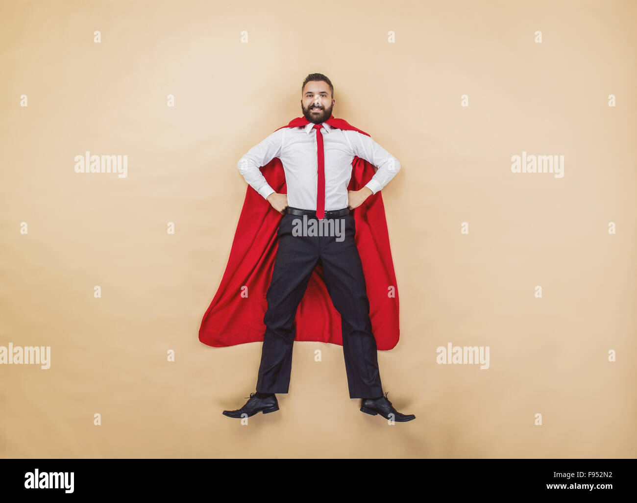Manager wearing a red superman cloak. Studio shot on a beige background. Stock Photo