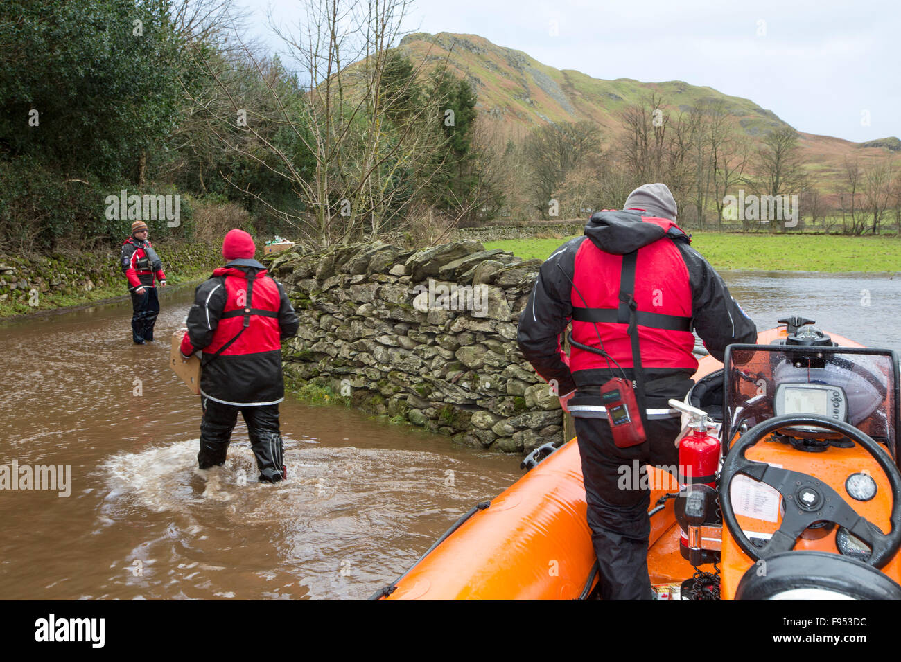 On Saturday 5th December 2015, Storm desmond crashed into the UK, producing the UK's highest ever 24 hour rainfall total at 341.4mm. It flooded the Lakeland village Glenridding, which was just starting to repair when another period of heavy rain on Wednesday 9th December caused the Glenridding Beck to burst its banks, causing yet further destruction. This photo taken the next morning on Friday 11th December shows Patterdale Mountain Rescue Team in their rescue boat, taking food supplies to Howtown on the other side of the Lake that has been cut off for five days by the floods. Stock Photo