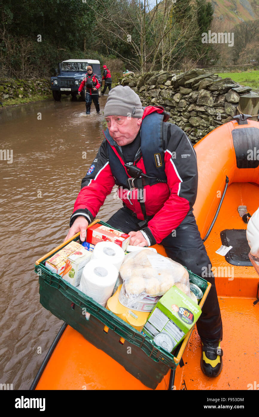 On Saturday 5th December 2015, Storm desmond crashed into the UK, producing the UK's highest ever 24 hour rainfall total at 341.4mm. It flooded the Lakeland village Glenridding, which was just starting to repair when another period of heavy rain on Wednesday 9th December caused the Glenridding Beck to burst its banks, causing yet further destruction. This photo taken the next morning on Friday 11th December shows Patterdale Mountain Rescue Team in their rescue boat, taking food supplies to Howtown on the other side of the Lake that has been cut off for five days by the floods. Stock Photo