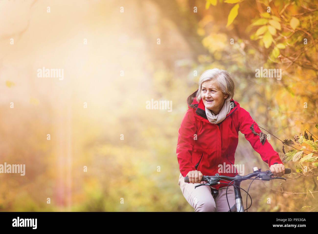 Active senior woman riding bike in autumn nature. Stock Photo