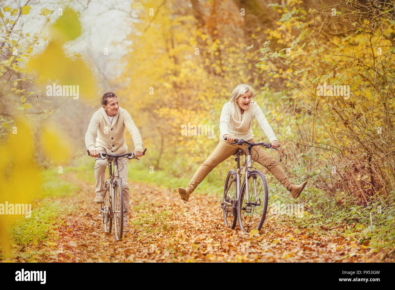 Active seniors riding bike in autumn nature. They having fun outdoor. Stock Photo