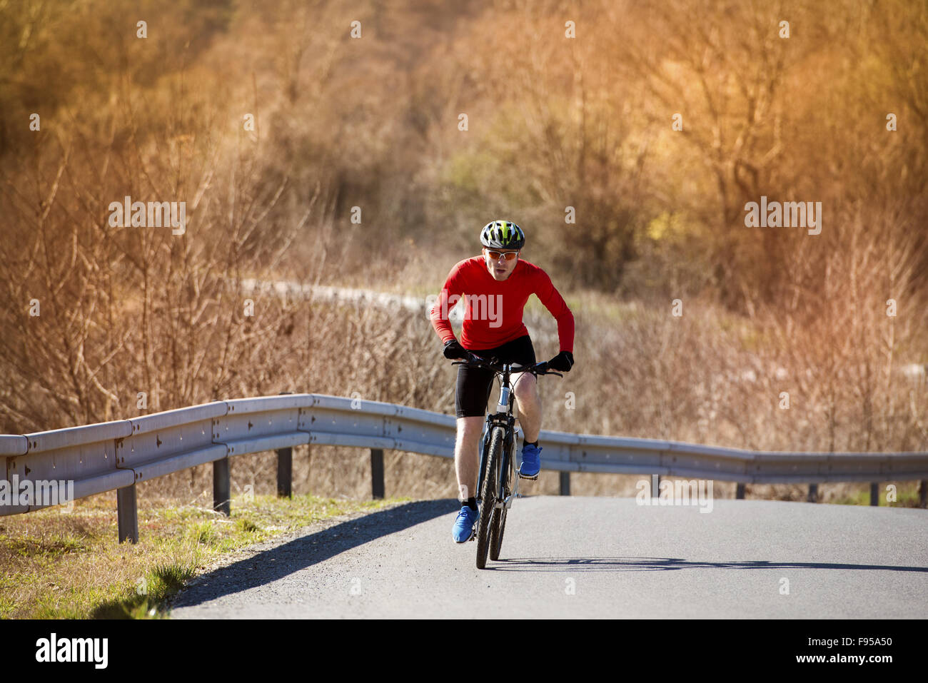Cyclist man riding mountain bike on asphalt road Stock Photo