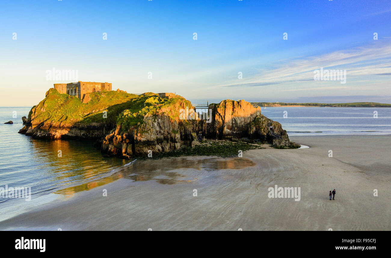 Two people walk on the sands close to St Catherine's Island, Tenby, Pembrokeshire, west Wales, UK Stock Photo