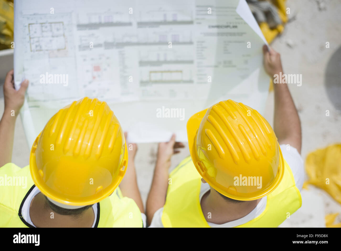 Engineer builders in safety vest with blueprint at construction site Stock Photo