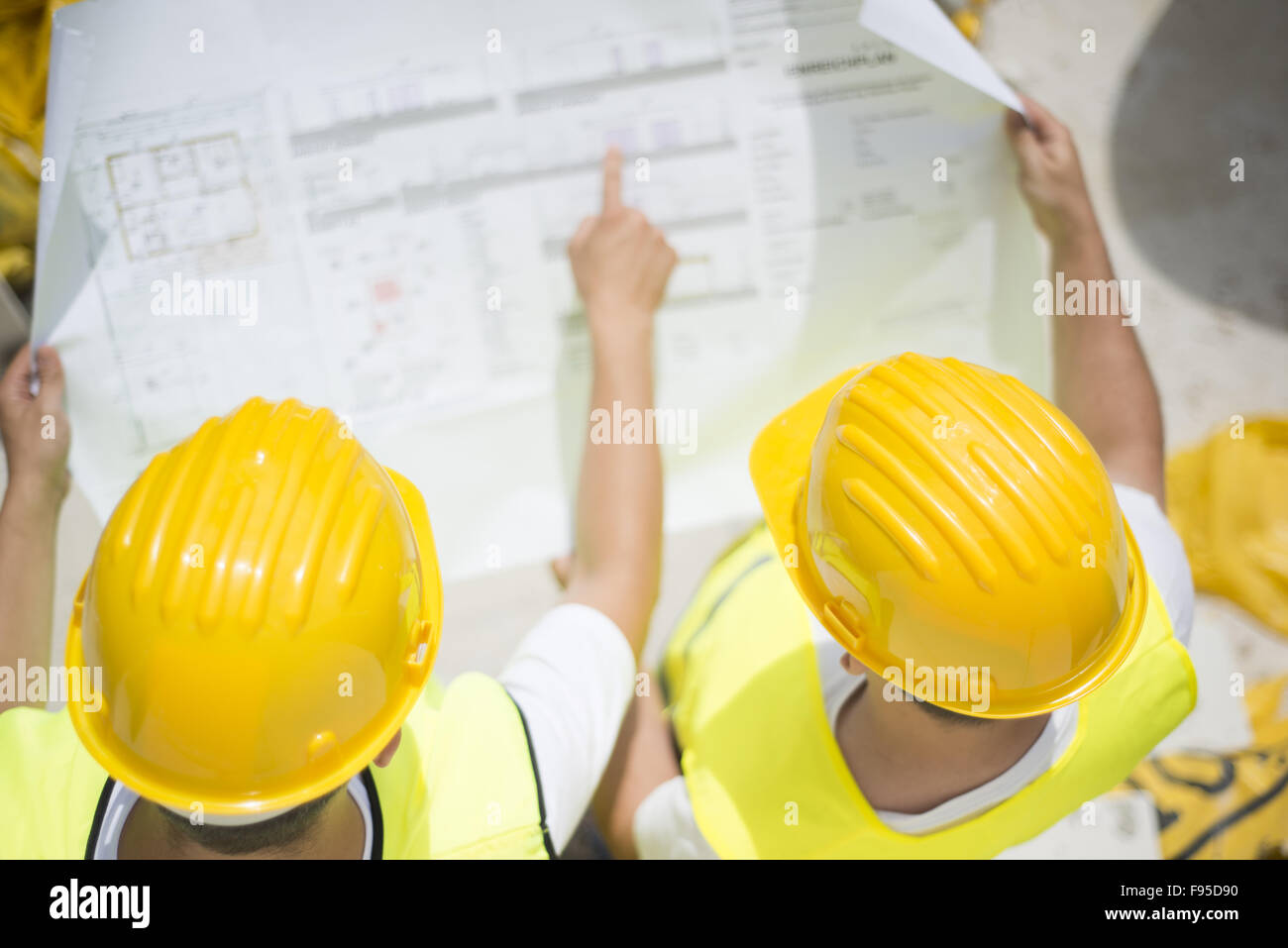 Engineer builders in safety vest with blueprint at construction site Stock Photo