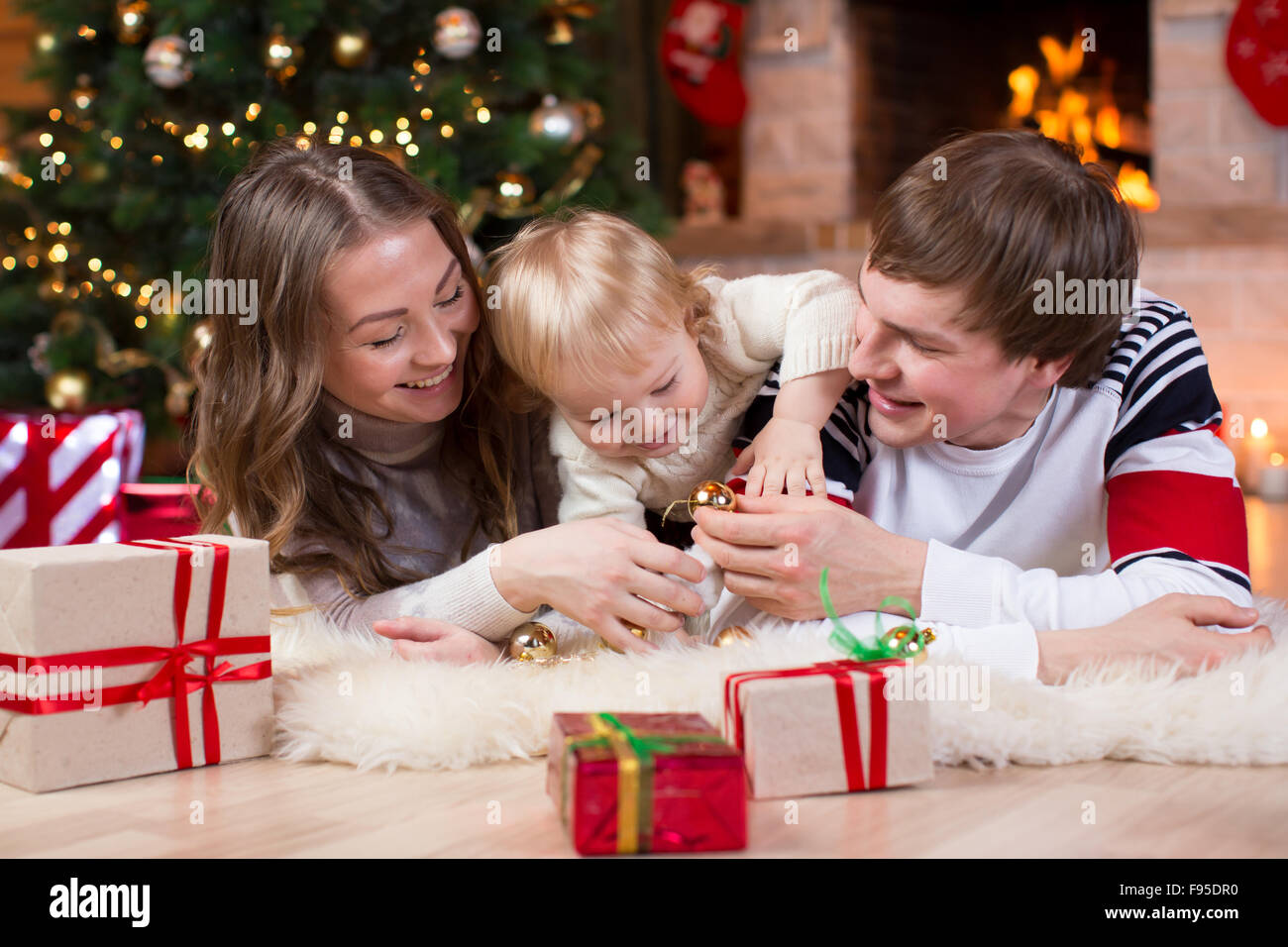 Happy family with little son have a fun pastime near Christmas tree and fireplace  in living room Stock Photo