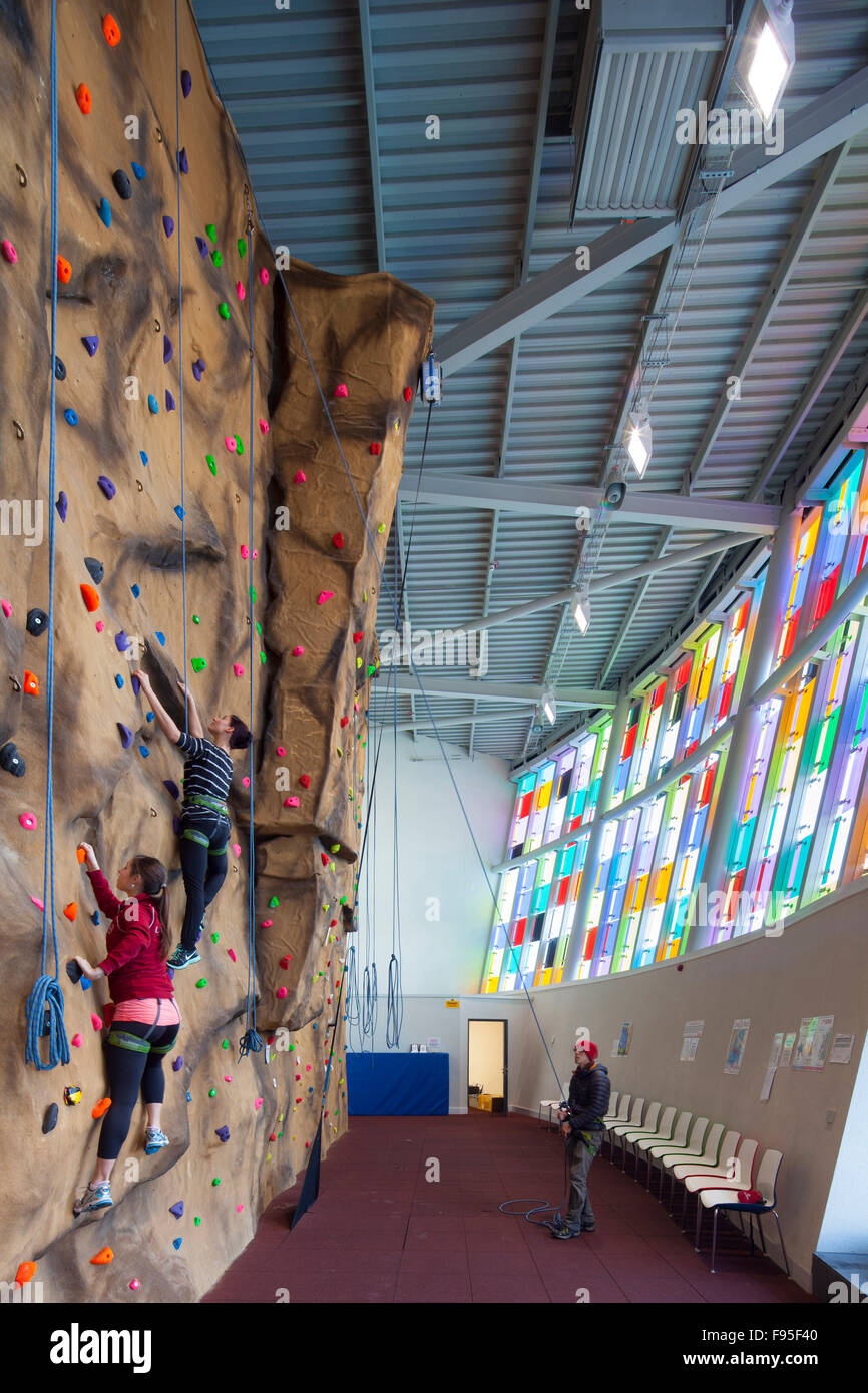The Glass Mill Leisure Centre is situated on the lowest three floors of a 27 storey apartment building in Lewisham. Visitors of the Leisure Centre using the inside rock climbing wall. Colourful glass tiles in view. Stock Photo