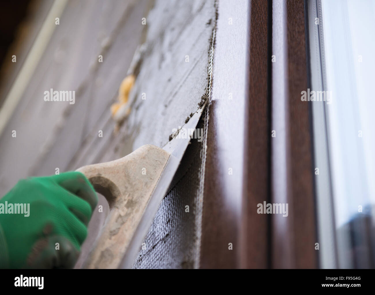 Plasterer spreading out plaster with trowel around the windows Stock Photo