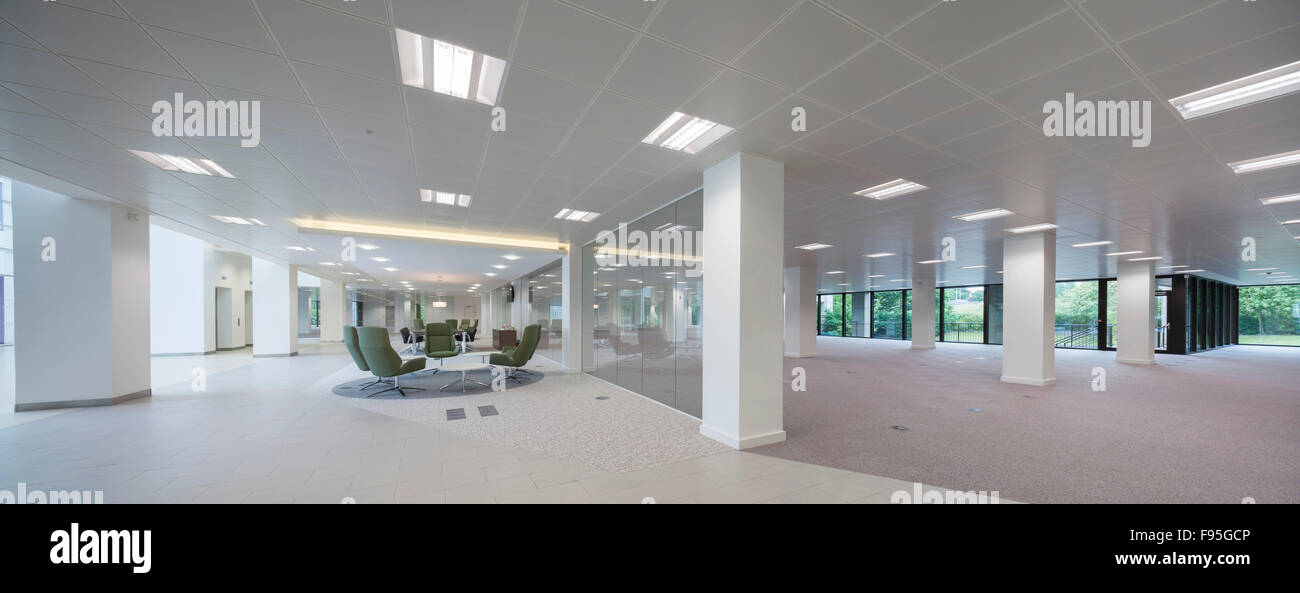 The Capitol Building, Bracknell. Distant view of office chairs and table in a modern styled floor of the Capitol Building. White walls and ceiling with skylights and ceiling to floor windows. Stock Photo