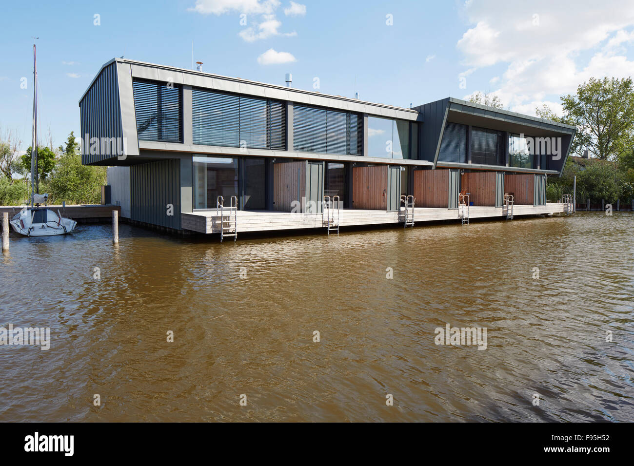 Housing development at Lake Neusiedl, Neusiedl am See, Burgenland, Austria. View across the water to the contemporary lakeside housing development. Extensive glass exterior walls. with mooring Stock Photo