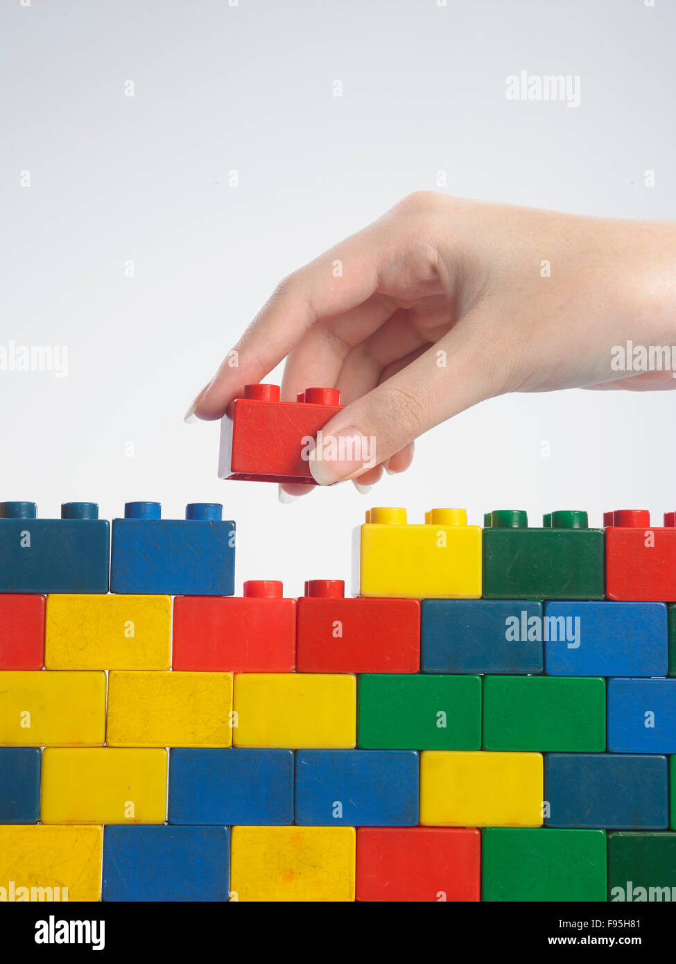 hand stack up lego set as a wall on white background Stock Photo