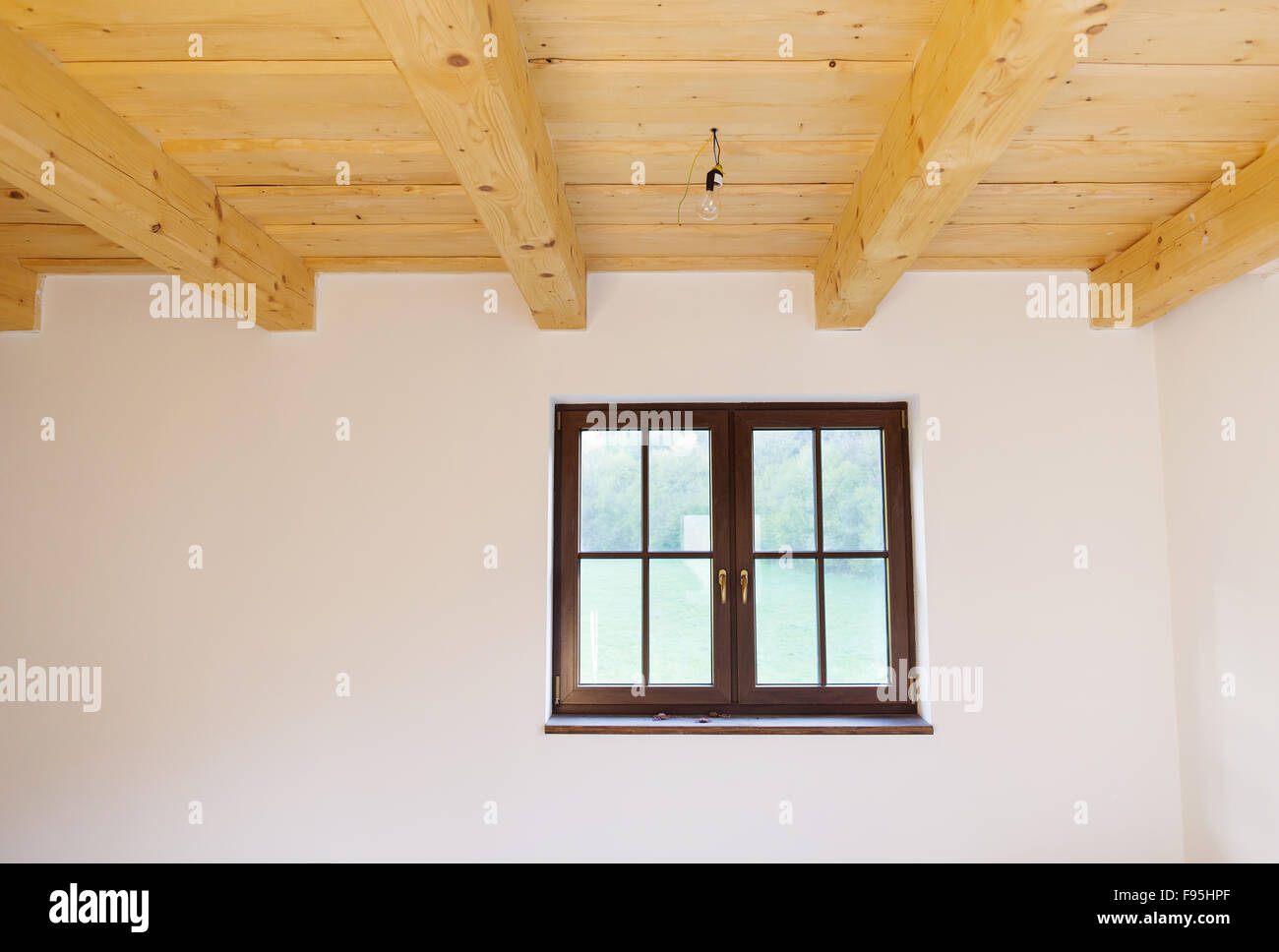 Empty unfinished room with white walls and wooden ceiling in a new constructed house Stock Photo