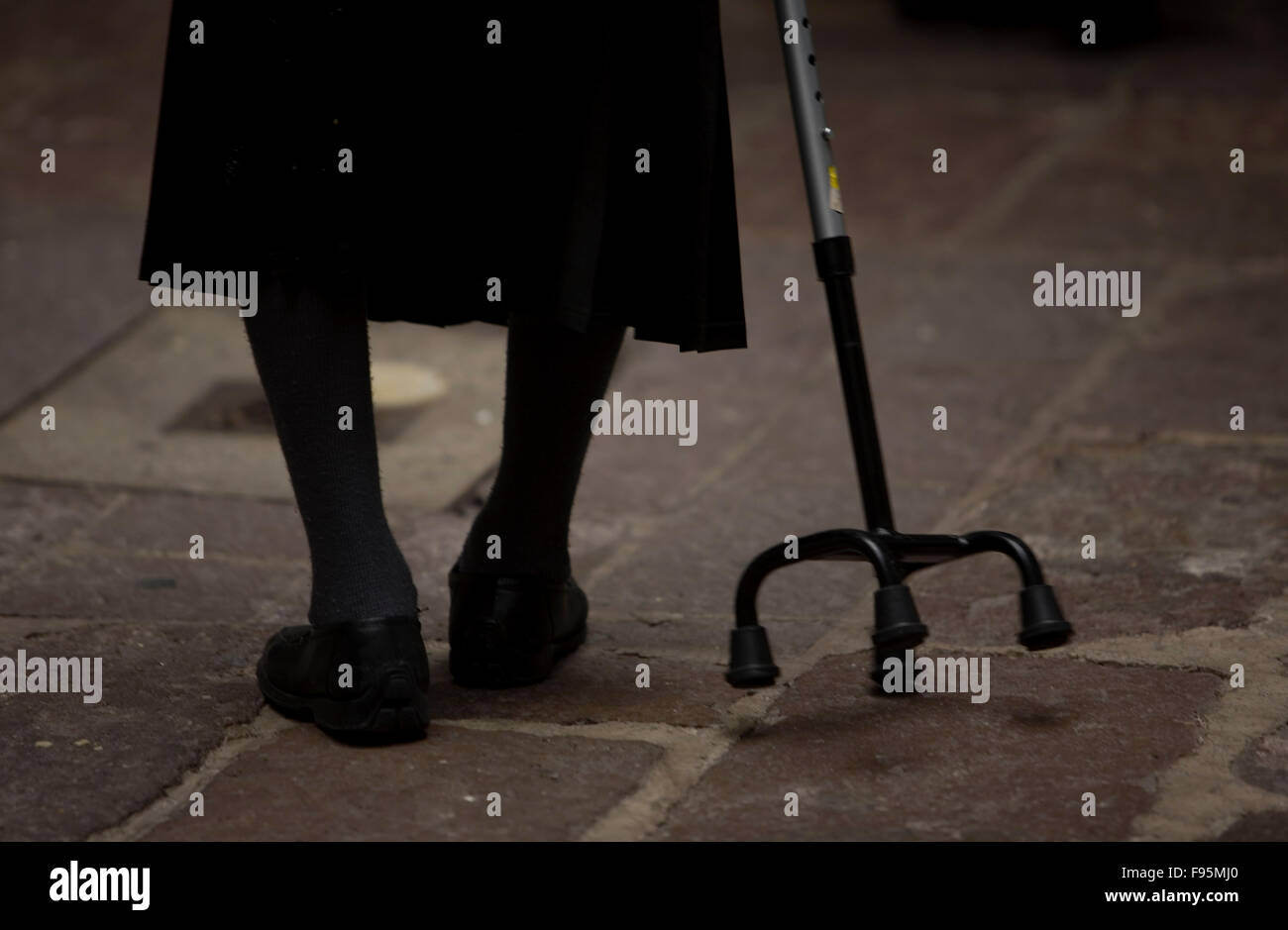 A woman uses a cane in the patio of in Our Lady of Guadalupe Home for the Elderly, Mexico City Stock Photo