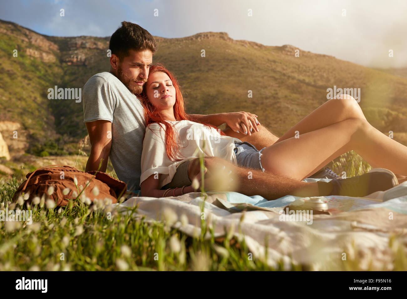 Portrait of loving young couple relaxing on summer picnic. Two young people on a mountain sitting together relaxing. Stock Photo