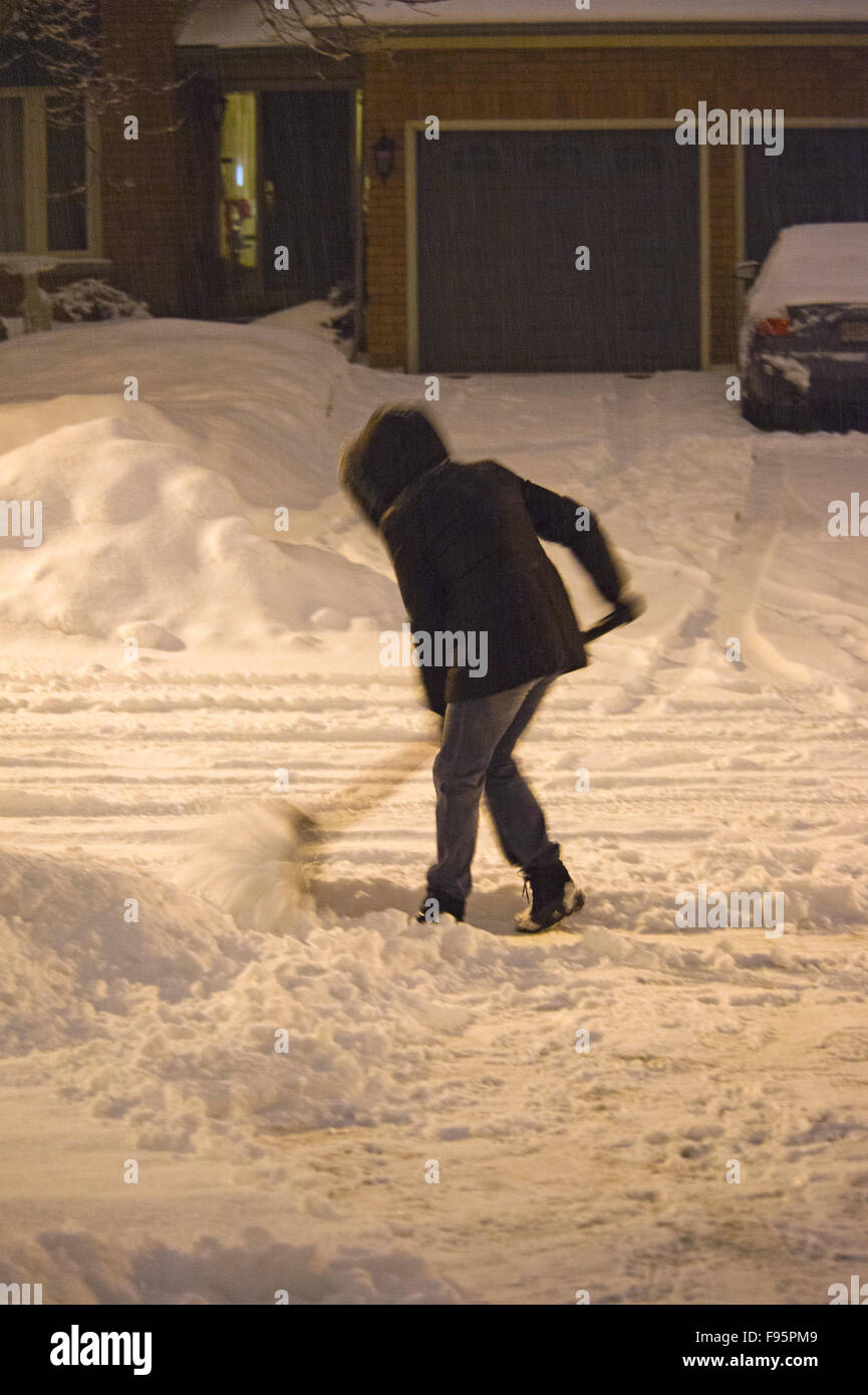 Woman cleaning snow from driveway after a snowstorm in Toronto suburbs