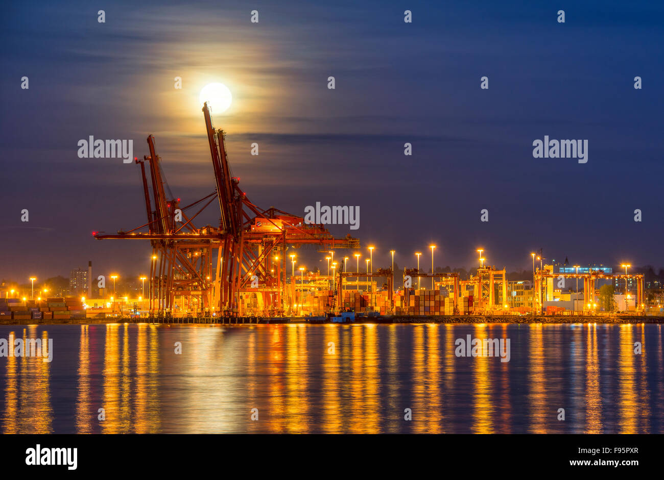 Moonrise over container cranes Stock Photo