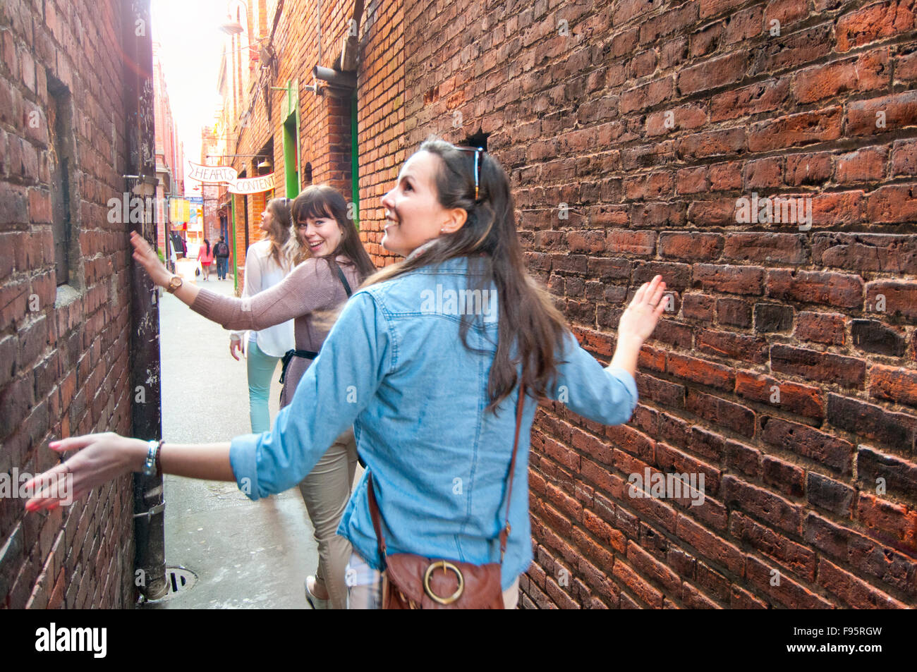 Young women are amazed at the narrow corridor of Fan Tan Alley, an area in Chinatown that features interesting shops in Stock Photo