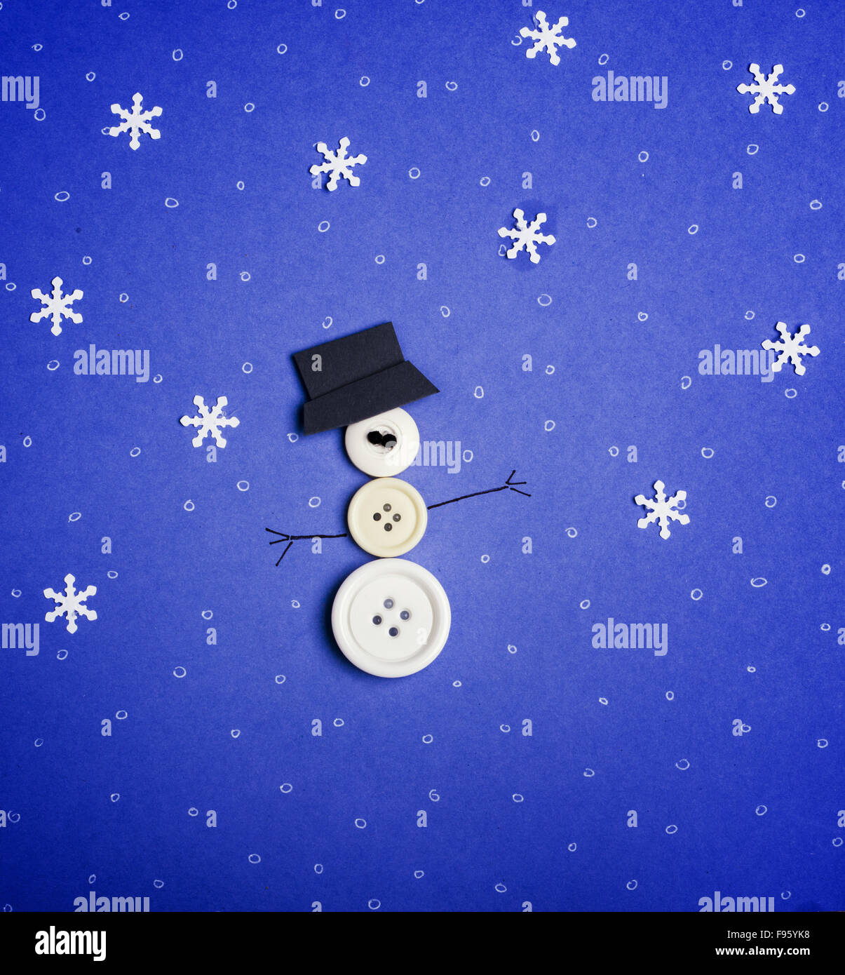 Winter background. Snowman made from buttons and snowflakes on blue
