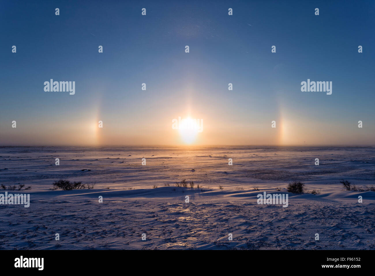 Sun dogs (parhelia) on either side of the sun low over the tundra, Cape Churchill, Wapusk National Park, Manitoba. Stock Photo
