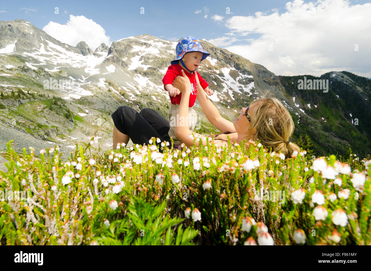 A young mother and her child lying in flower meadows at Alps Alturas near New Denver, British Columbia Stock Photo